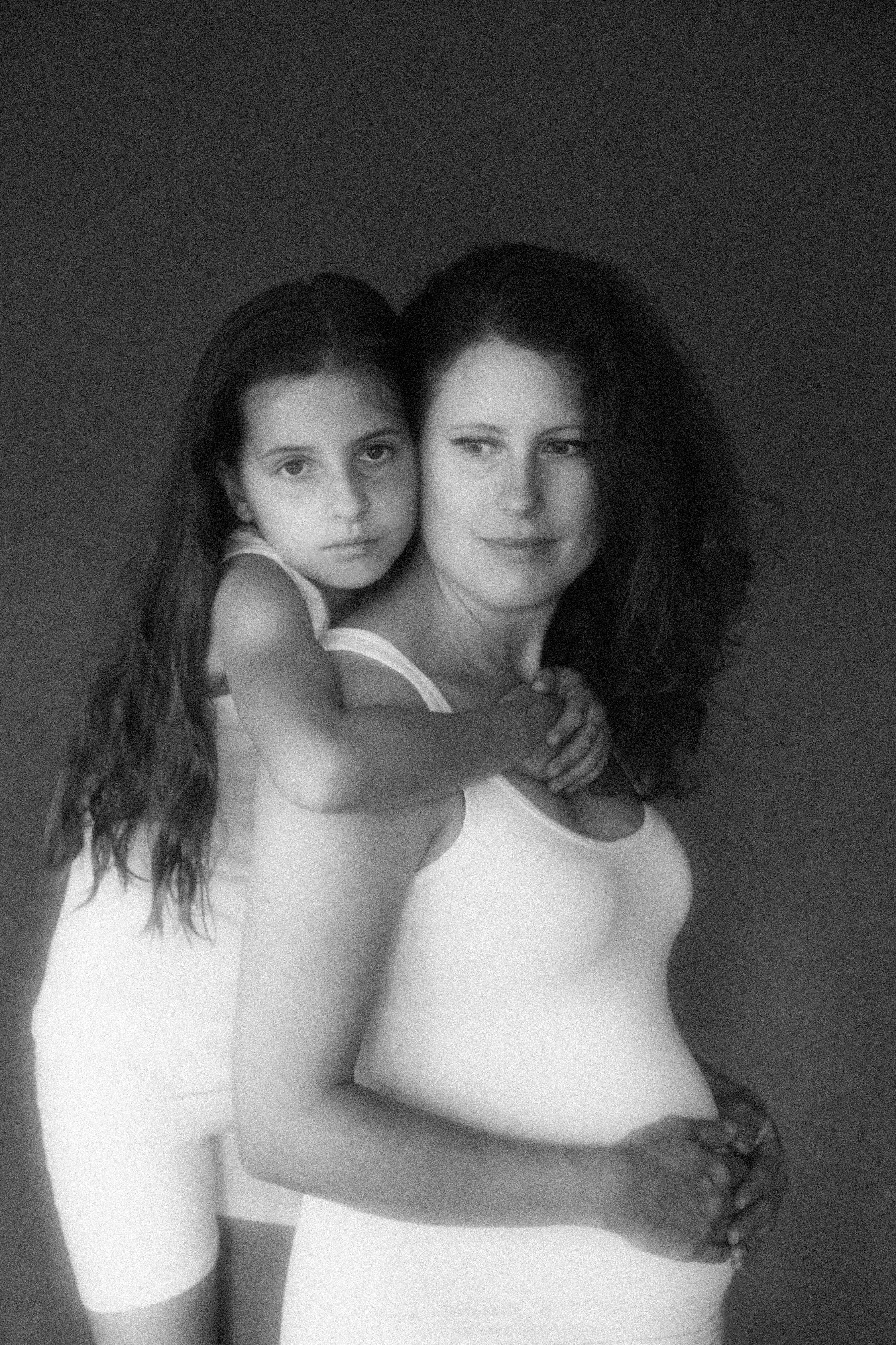 Intimate black and white maternity portrait of a mother and daughter in soft glowing light